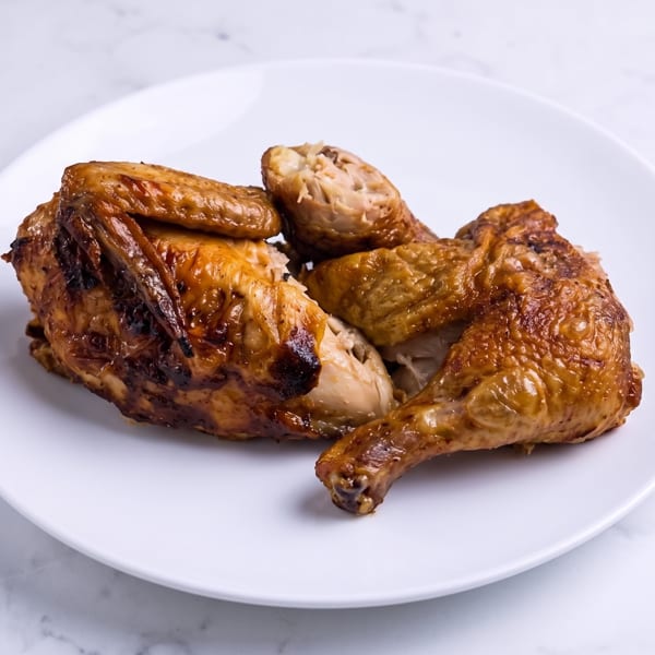 Plate of roasted chicken pieces with browned, crispy skin and exposed meat.